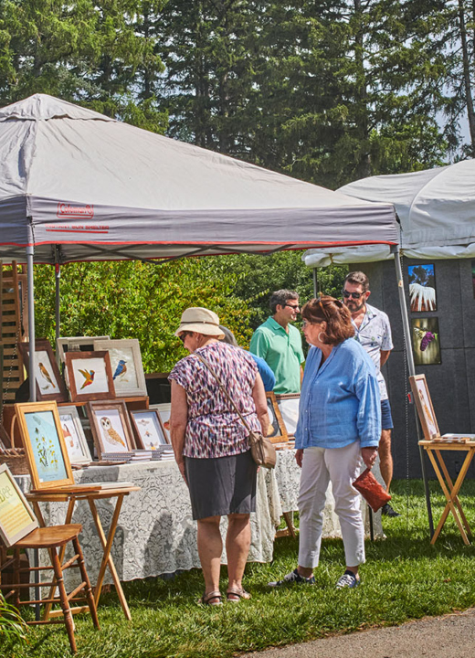 Guests look at artworks displayed in tents during The Morton Arboretum's Wine and Art Walk.